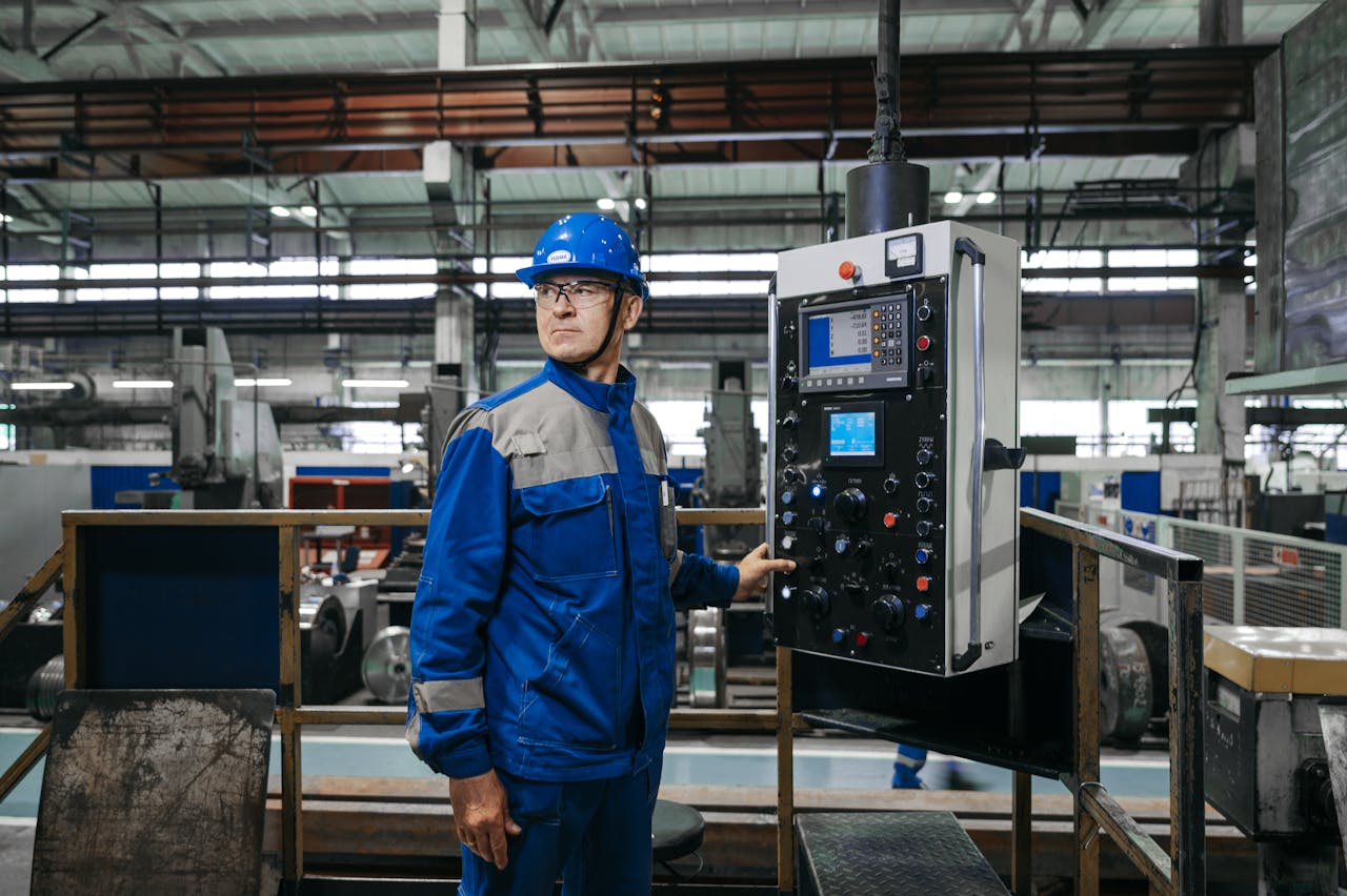 Male factory worker in protective gear operates machinery indoors.