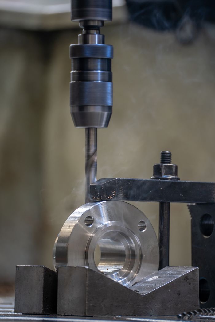 Services Close-up view of a metal drilling process in an industrial workshop setting.